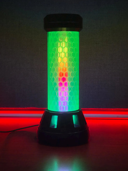 A cylindrical LED light bar with a black base and top, featuring a honeycomb-patterned translucent body that glows with a green-to-yellow-to-red gradient and pink accents, set against a dark background with red ambient lighting.